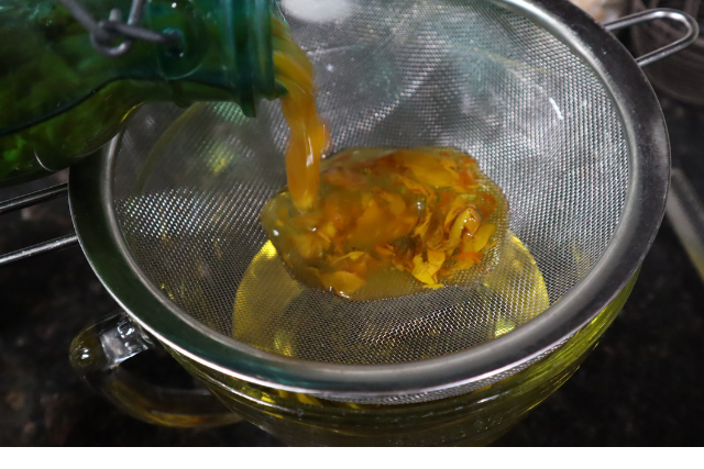 Straining my herbs by pouring oil infusion over a strainer.